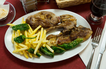 Baked tasty lamb chops served with fried potatoes and green pepper at plate