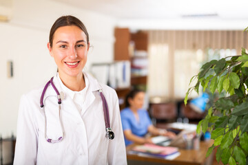 Portrait of positive female doctor wearing uniform standing with stethoscope in modern clinic