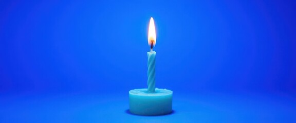 Fototapeta premium Single blue birthday candle on a vibrant blue background, desire, celebration