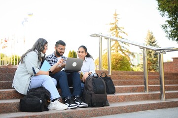 group of young students checking exam results or waiting for project approval on laptop at collage campus