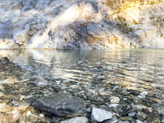 Obraz premium mountain river with crystal clear water and visible stones under the surface. natural landscape with soft sunlight reflections and rocky