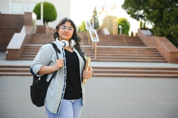 Fototapeta premium Portrait of a cheerful smart student girl studying with books. Indian student educational young teenager girl at outside campus