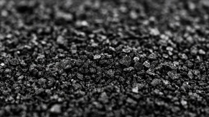 Close-up view of fine black sand grains scattered across a surface, creating a textured background ideal for design