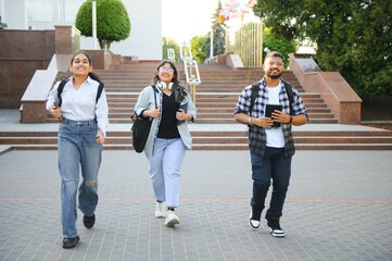 Fototapeta premium Three international students standing and holding a books