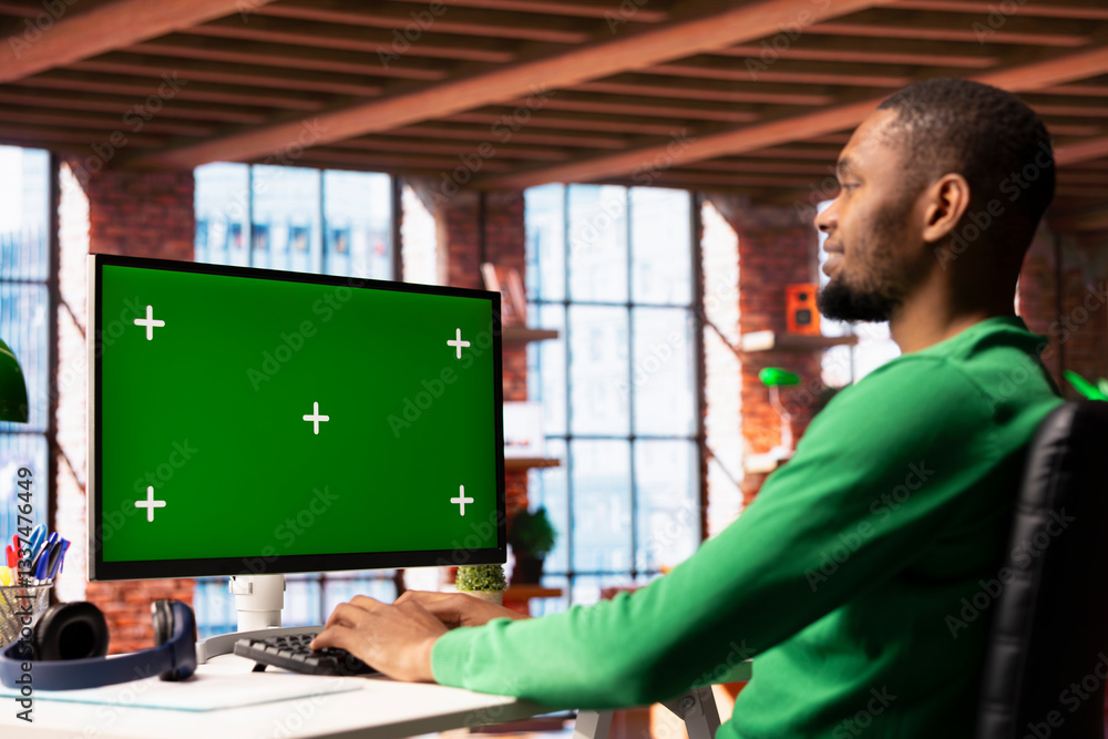 Poster smiling man enjoying leisure time in apartment, using green screen pc screen to text friends. happy 