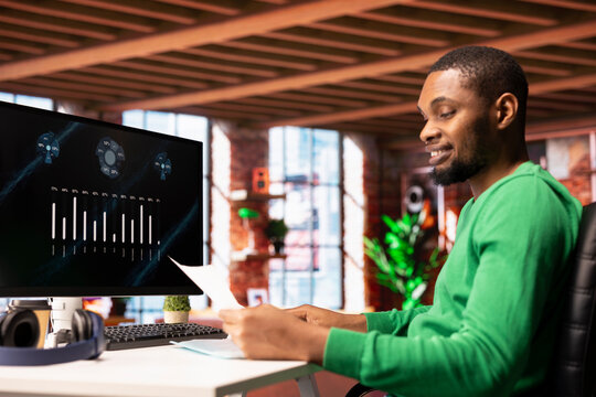 Upbeat teleworker using financial software user interface on PC screen in apartment showing company growth graphs. Man looking at sales statistics on computer display showing income figures