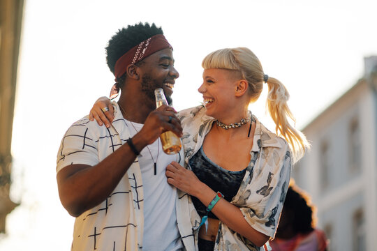 Happy multiethnic couple drinking beer at summer music festival