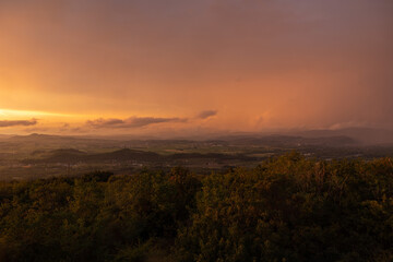vista panoramica su parte del territorio tra pianura e collina, nella regione Friuli Venezia Giulia, dopo un temporale estivo, al tramonto, con le nuvole colorate di arancione dalla luce del sole