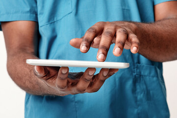 A millennial African American doctor utilizes a tablet for healthcare tasks in a clinical...
