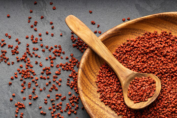 Organic red annatto seeds in spoon and bowl - Bixa Orellana