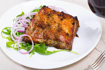 Juicy barbecue rack of pork served on fresh arugula with onion rings