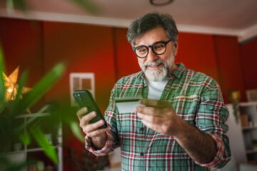 mature happy man use mobile phone and credit card for online shopping