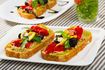 Image of sandwich with canned tuna and vegetables on the plate indoors.