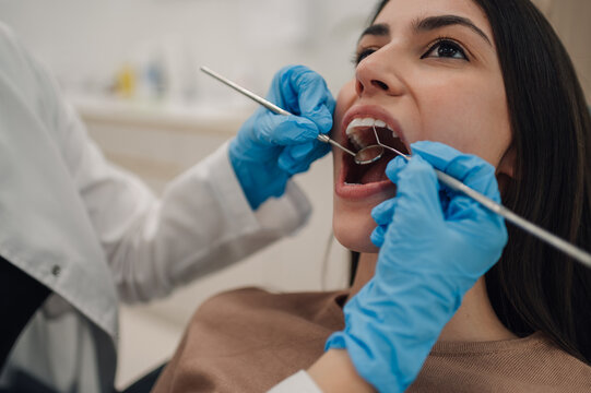 Dentist examining patient's teeth with dental instruments in clinic