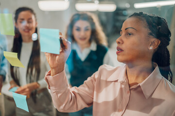 Focused businesswoman writing on sticky notes during brainstorming session