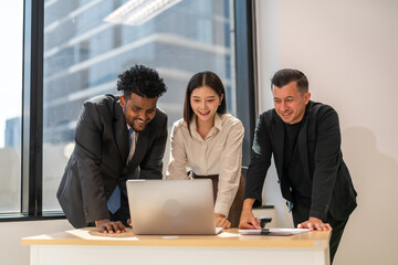 Diverse group of business professionals in formal collaborating during a corporate meeting, focused on technology and teamwork, asian businesswoman leading with laptop, teamwork and collaboration