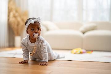 Cute african baby with pacifier crawling on floor, innocent childhood at home, sweet infant comfort, playful and happy toddler, parenting and care concept, adorable little girl exploring environment
