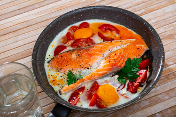 Healthy omelet with salmon steak and tomato served in frying pan