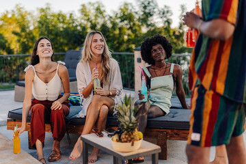 Friends enjoying drinks by the poolside at a summer party