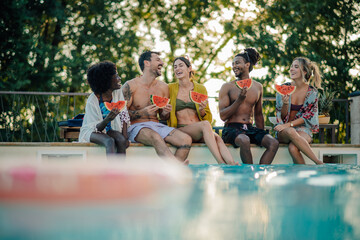 Happy friends eating watermelon by the poolside during summer vacation