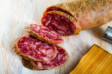 Spanish salchichon sausage cut in slices on a wooden surface, close-up