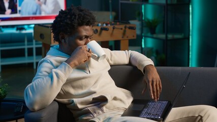 Positive african american man multitasking on a laptop in stylish loft, fully connected to the...