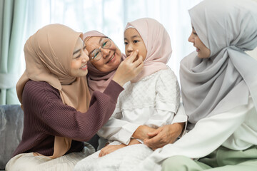 Obraz premium Four generations of muslim woman in hijab enjoying family time showing love, joy and happiness, grandmother, mother, daughters and granddaughter celebrating family traditions, togetherness and support