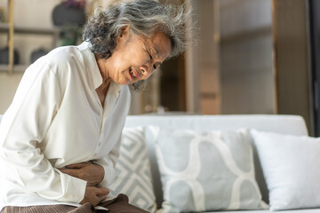 Elderly asian woman experiencing stomach pain, health problem, senior female suffering from...