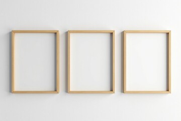 Three empty light brown wooden picture frames hang on a white wall , simple, display, light wood