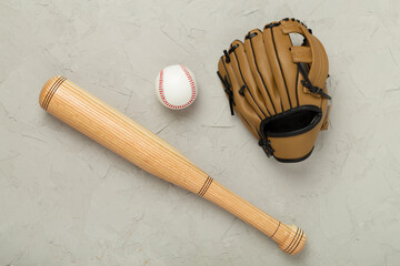 Baseball glove and bat with ball on concrete background, top view