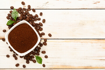 Roasted coffee beans with leaves on wooden background,top view