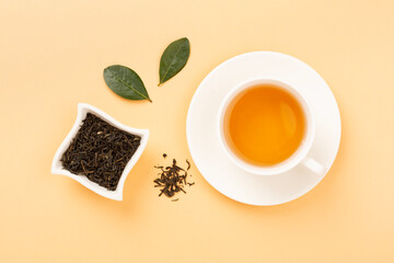 Cup of tea with dry and fresh leaves on color background, top view