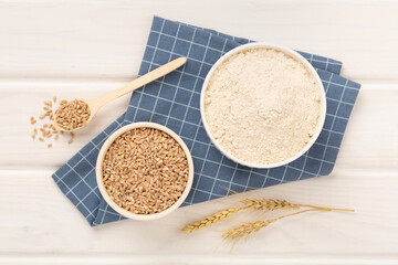 Bowl with spelt flour on wooden background, top view