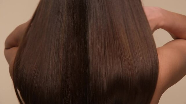 Beautiful woman with brown healthy hair on beige background. Hair beauty.