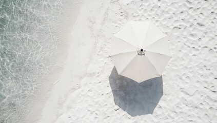 Aerial view of a lone umbrella on a pristine white sandy beach.