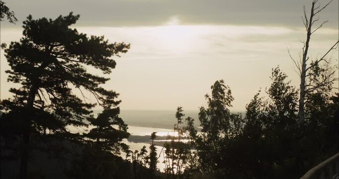 Bright sunlight shining over lake and forest at sunset
