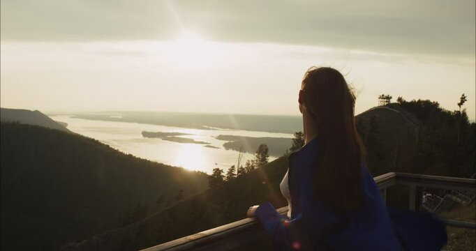Woman enjoying sunset over river and hills from viewpoint