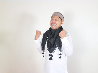 Handsome Asian man in Muslim clothes on white isloted background showing successful gesture, achieving victory