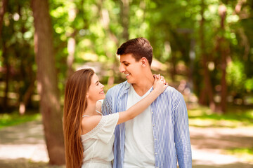 Obraz premium Beautiful girl looking at her boyfriend with love and hugging him at park