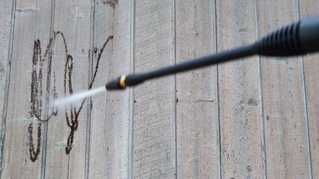 Power washing old paint off the wood siding of a house