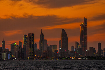 Stunning Kuwait City Skyline at Twilight with Illuminated Skyscrapers and Fiery Sunset Over the Arabian Gulf © Emad Aljumah
