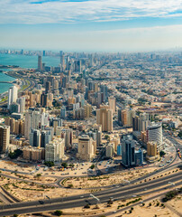 Fototapeta premium Aerial View of Kuwait City Skyline with High-Rise Buildings, Coastal Road, and Urban Landscape on a Clear Day – Kuwait
