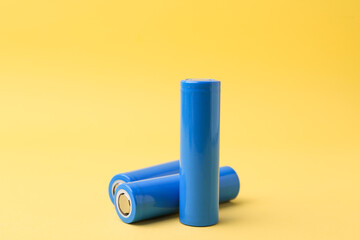 Three AA cell batteries on yellow background, closeup