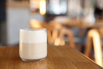 Glass of aromatic coffee on wooden table in cafe, closeup. Space for text