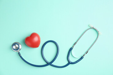 Cardiology. Stethoscope and red decorative heart on turquoise background, flat lay. Space for text