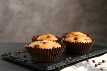 Delicious muffin with chocolate chips on black table, closeup