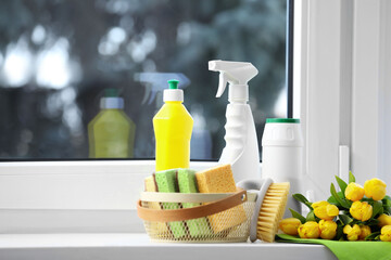 Spring cleaning. Detergents, supplies and yellow tulips near window indoors, space for text