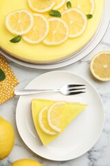 Tasty lemon cheesecake, mint, citrus fruits and fork on white marble table, flat lay