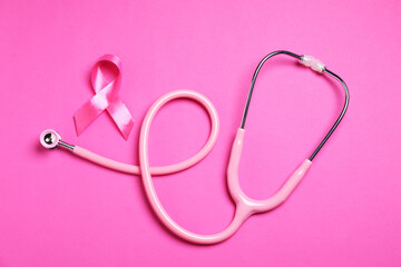Breast cancer awareness. Pink ribbon and stethoscope on color background, top view