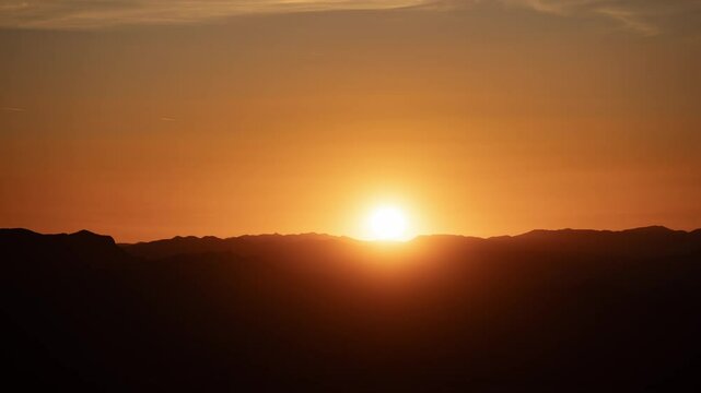 Time lapse of an orange sunset over desert mountains